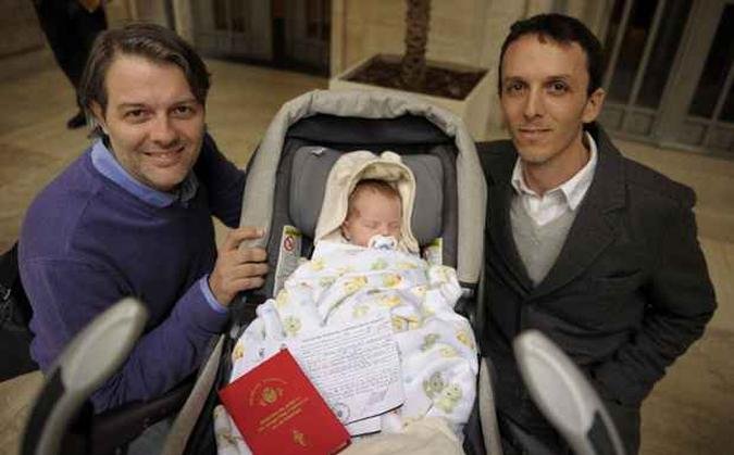 Carlos Grinblat e Alejandro Dermgerd mostram a crian�a adotada e a certid�o de nascimento do filho(foto: JUAN MABROMATA / AFP)