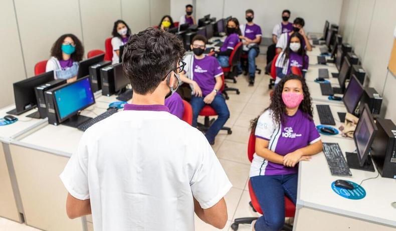 Professor, de costas, em sala de aula cheia.