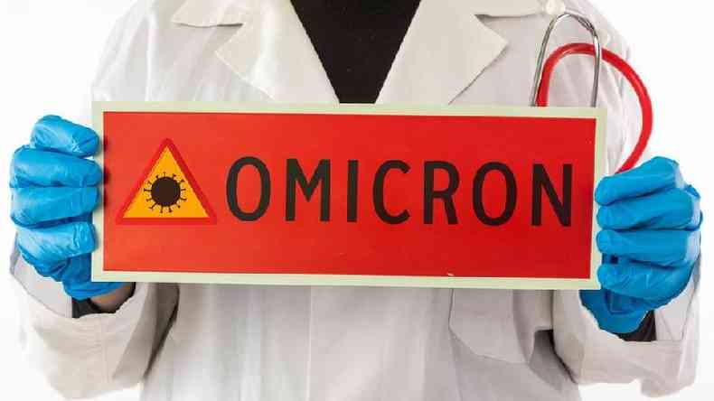 Pessoa com luva segura placa em que se lê: ômicron