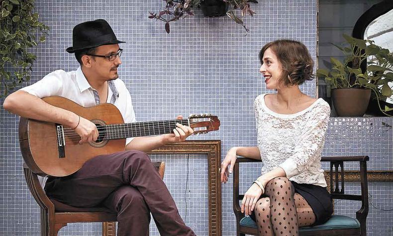 Felipe Borim toca violo olhando para Camila Brasiliano. Os dois sorriem um para o outro