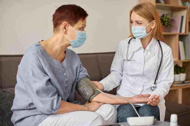 Médica aferindo a pressão arterial da paciente