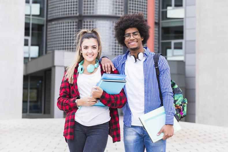 (foto: Freepik) Dois jovens em frente uma instituição educacional