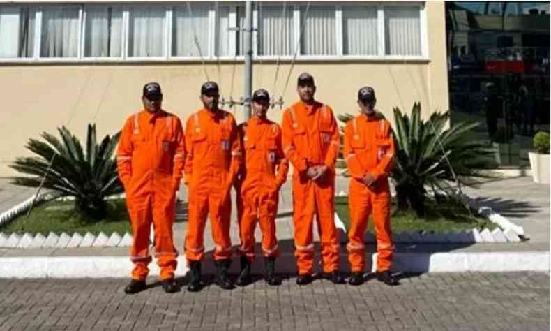cinco homens com roupas laranjas 