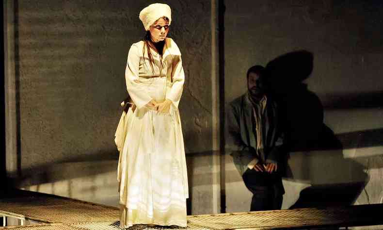 A atriz Debora Falabella, de figurino branco, est no centro do palco, e Luiz Arthur atrs,  direita, na pea Noites brancas