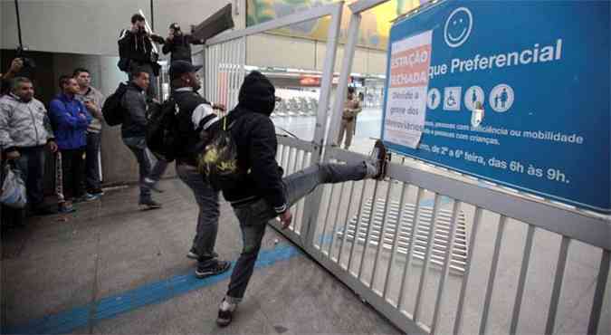 Homens chutam as grades dos portes de entrada da estao Itaquera em So Paulo(foto: REUTERS/Chico Ferreira)