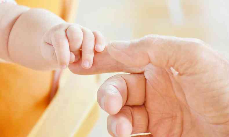 Mozinha de beb segura o dedo de um adulto