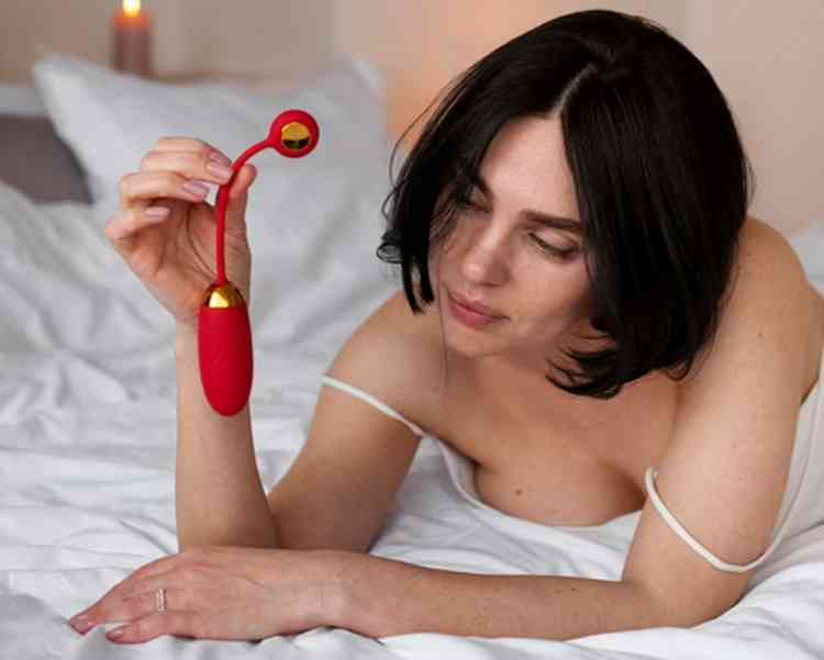 Mulher na cama segurando vibrador