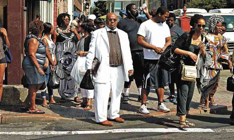 Grupo de pessoas aguarda na calada de uma rua do Harlem para atravessar a rua
