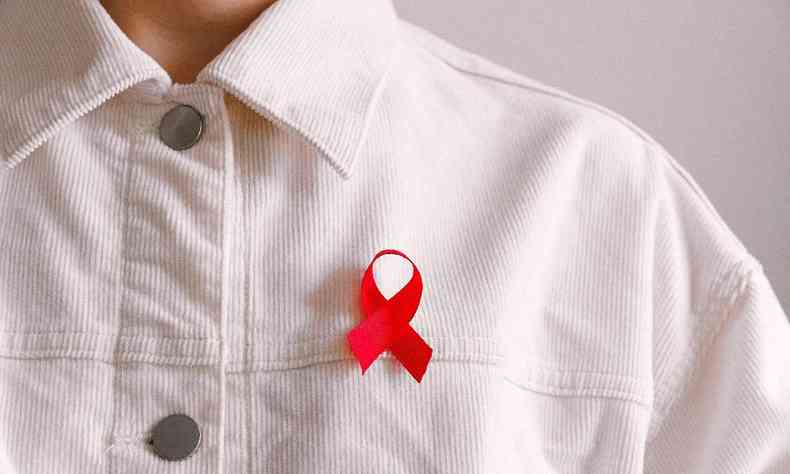 Pessoa usando blusa de veludo canelada branca dom a fita vermelha do combate  aids no peito