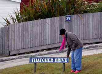 Mulher toca placa de identificao de via pblica batizada em homenagem a Margaret Thatcher, em Stanley, nas ilhas Malvinas (foto: REUTERS/Marcos Brindicci )