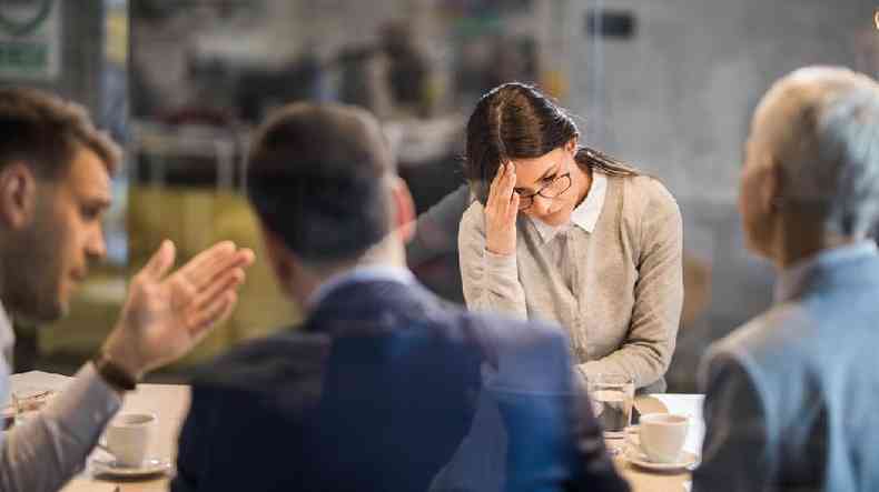 quatro pessoas brancas em uma sala de reunio, um homem parece discutir e uma mulher parece chateada
