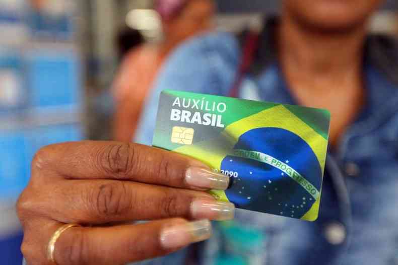 Mulher segurando o carto do auxlio brasil