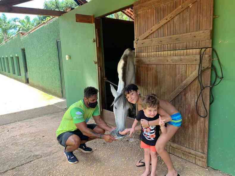 Recreador e crianas alimentam cavalo em hotel fazenda 
