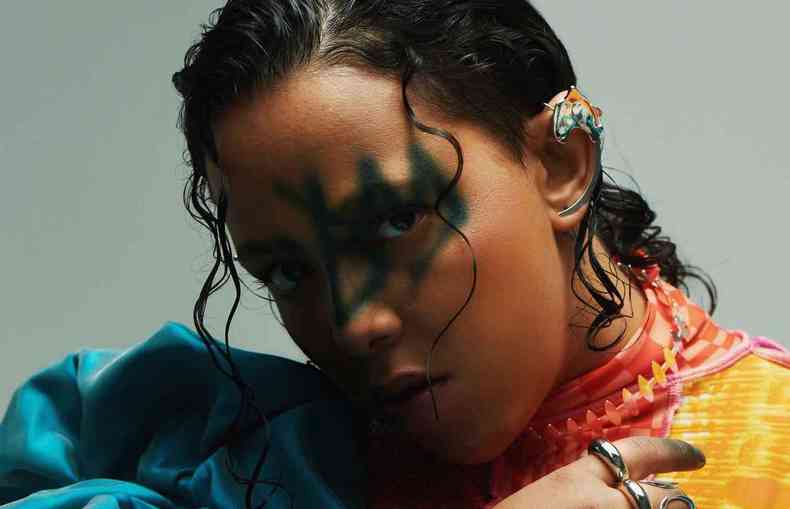 A artista Badsista posa com o rosto maquiado, roupas volumosas e anis nos dedos 