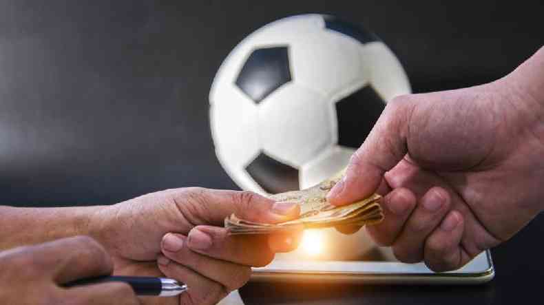 Mos segurando dinheiro em frente  bola de futebol