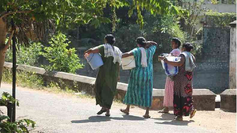 Mulheres indianas caminham até um rio para lavar roupa
