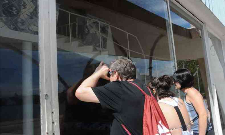 Com a igrejinha fechada, Marcelo Land, Juliana Garcia e a filha Jlia do uma espiada pela vidraa do templo e criticam o ar de abandono(foto: Paulo Filgueiras/EM/DA Press)