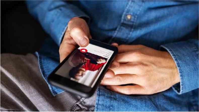 Fotografia colorida mostra uma mo segurando um celular aberto no Tinder