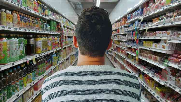 homem de costas em um corredor de bebidas num supermercado
