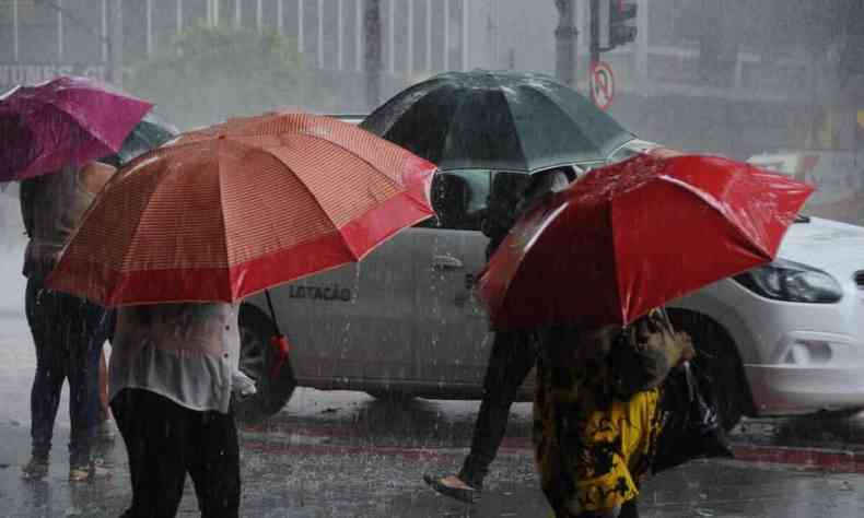Pessoas se protegem da chuva com sombrinha no Centro da capital 