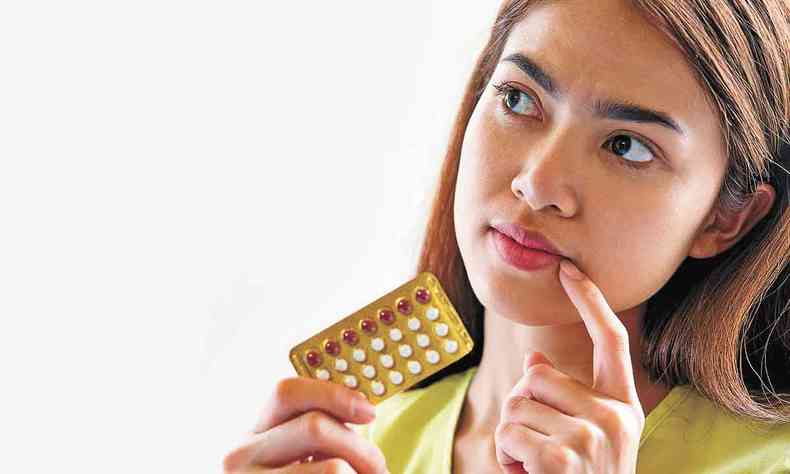 mulher segurando cartela de anticoncepcional