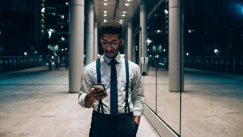 Homem de gravata e suspensrios olhando um celular
