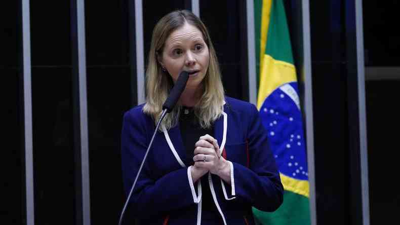 Deputada discursando no plenrio da Cmara com bandeira do Brasil ao fundo