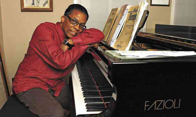 Pianista Herbie Hancock está sentado, recostado ao piano