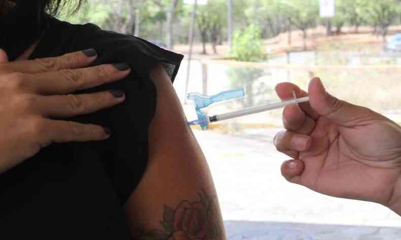 Mulher recebendo dose de vacina contra a COVID-19 para pessoas de 46 anos