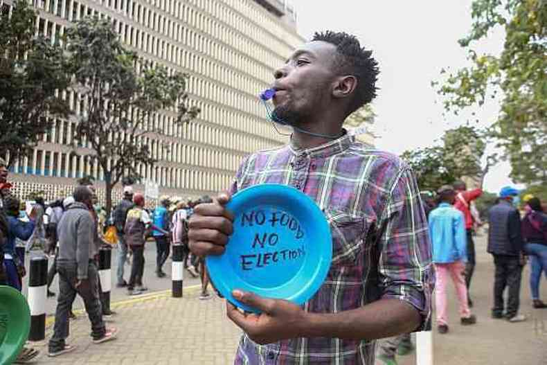 Homem queniano durante protesto contra a inflao, com um apito na boca e segurando um prato vazio onde se l: 'Sem comida, sem eleio'
