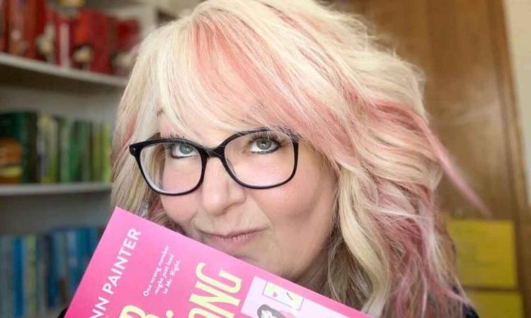 Escritora Lynn Painter segura livro com capa rosa-choque