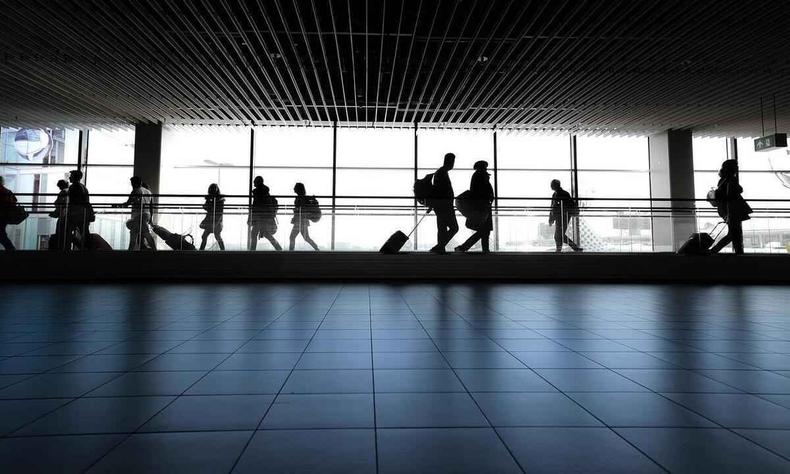 pessoas em aeroporto carregando malas