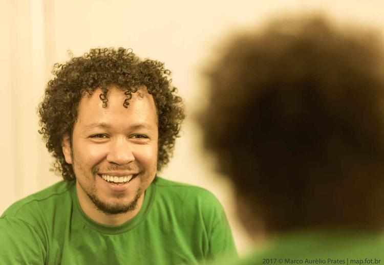 De camiseta verde, o produtor Victor Magalhes sorri para a cmera
