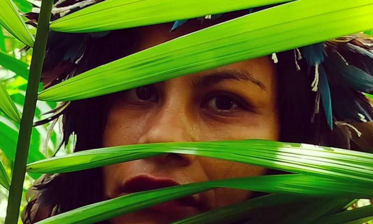 Poeta Marcia Kambeba olha para a cmera, atrs de folhas verdes