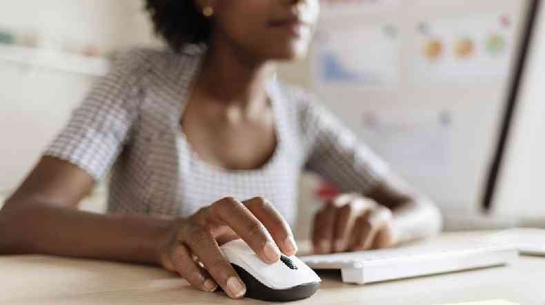 Mulher desfocada usando um computador com mouse e teclado brancos