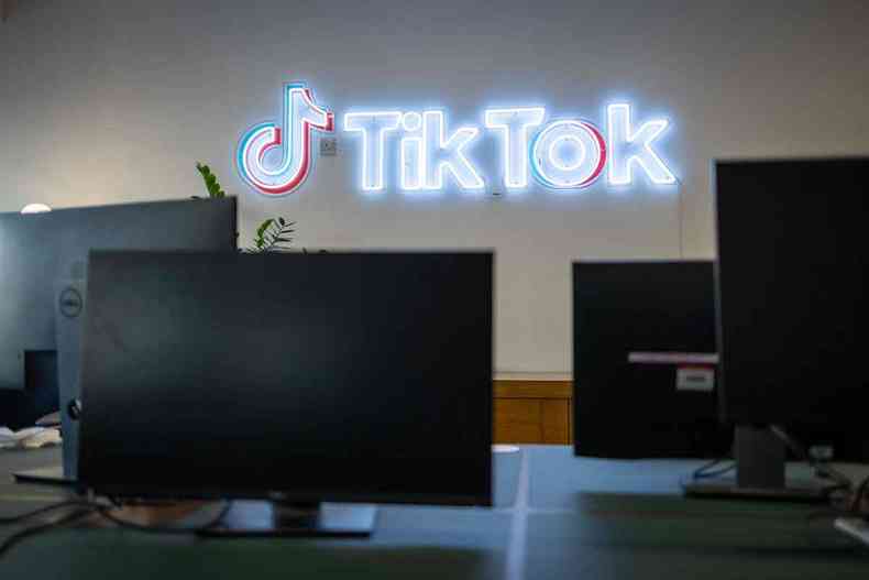 Sala com computadores e display neon na parede escrito TikTok 