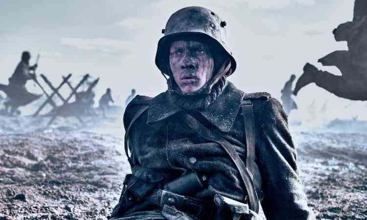 Soldado no meio da guerra, com rosto assustado, em cena do filme Nada de novo no front