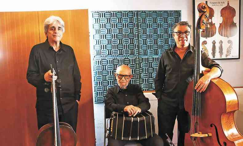 Vestidos de preto, em sala decorada, Antonio Viola (de p), Rufo Herrera (sentado) e Fernando Santos (de p) posam com seus instrumentos