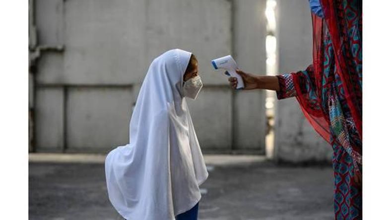 Menina com vu e mscara tem a temperatura medida