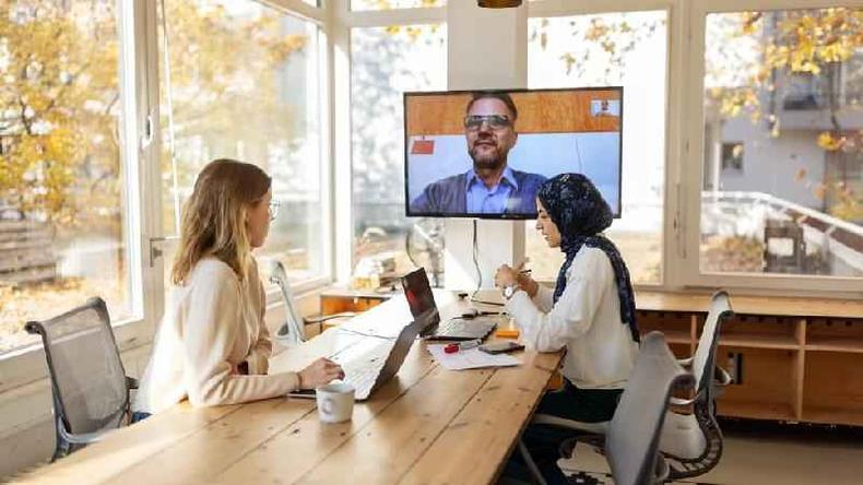 Reunio de trabalho hbrida em escritrio com participao de funcionrio por videoconferncia
