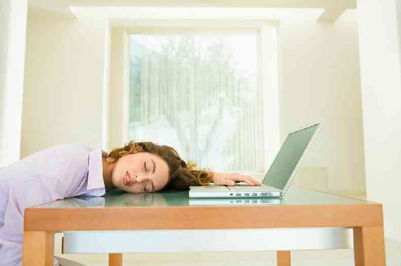 Mulher exausta diante do notebook
