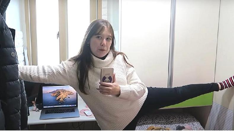 Thais Midori mostra seu apartamento em Seul, com a mo em uma parede e o p encostando na parede oposta