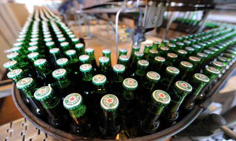 Vrias garrafas de cerveja de cor verde em uma esteira