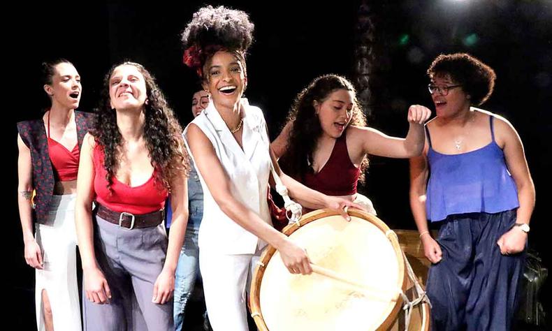 Atrizes cantam, tocam tambor e sorriem ao encenar a pea Plataforma 23 