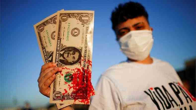 Manifestante exibe notas com rosto de Bolsonaro sujas de sangue em referncia s denncias de pedido de propina em contratos de compra de vacinas(foto: Reuters)