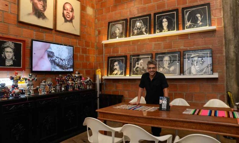 Franklin Brito Arajo, o FKL, est com as mos sob a mesa. Atrs dele, nas parede, esto os quadros que pintou