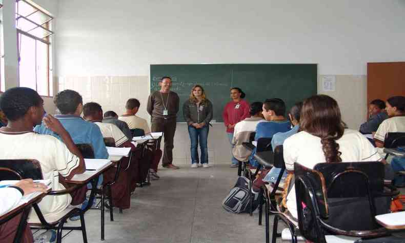 Alunos dentro de uma sala de aula, com trs adultos na frente do quadro verde