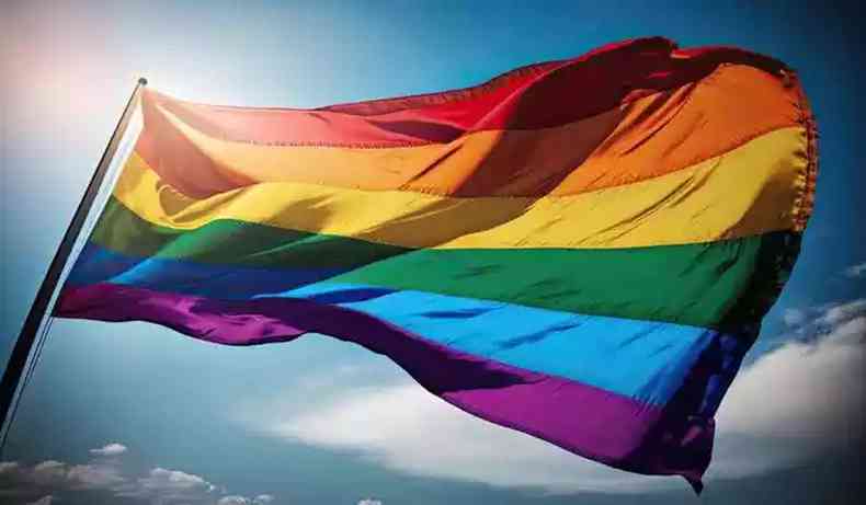 Bandeira LGBT com as cores do arco-ris est hasteada com um cu azul ao fundo