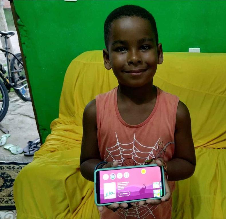 Menino sorri e mostra a tela de celular para a cmera