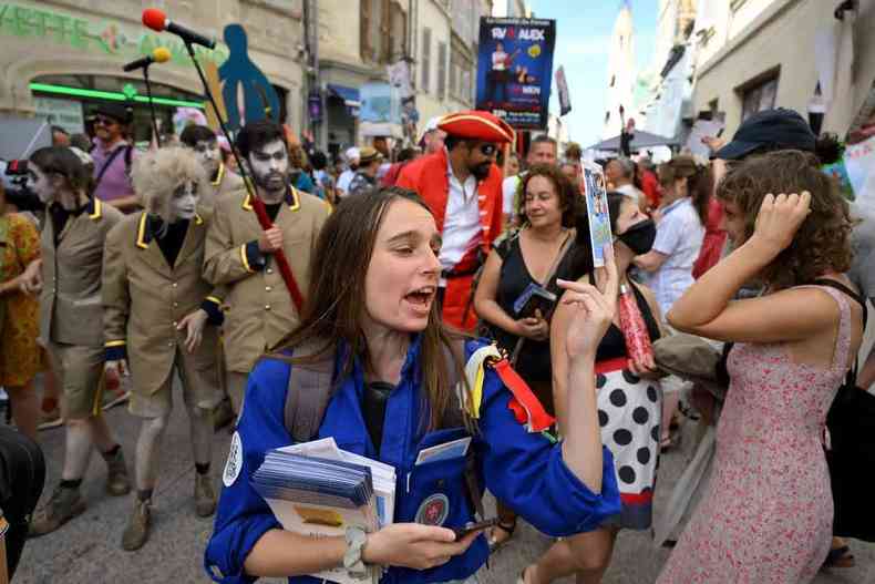 Maquiados e com roupas chamativas, atores circulam pelas ruas de Avignon, distribuindo panfletos de suas peças 